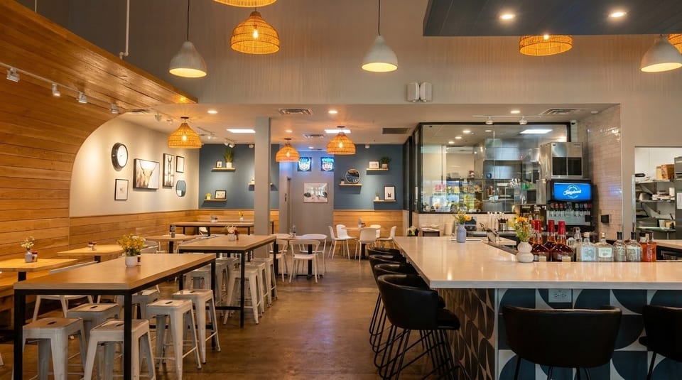 Modern restaurant interior with wooden accents, blue walls, various seating, and a bar with bottles.