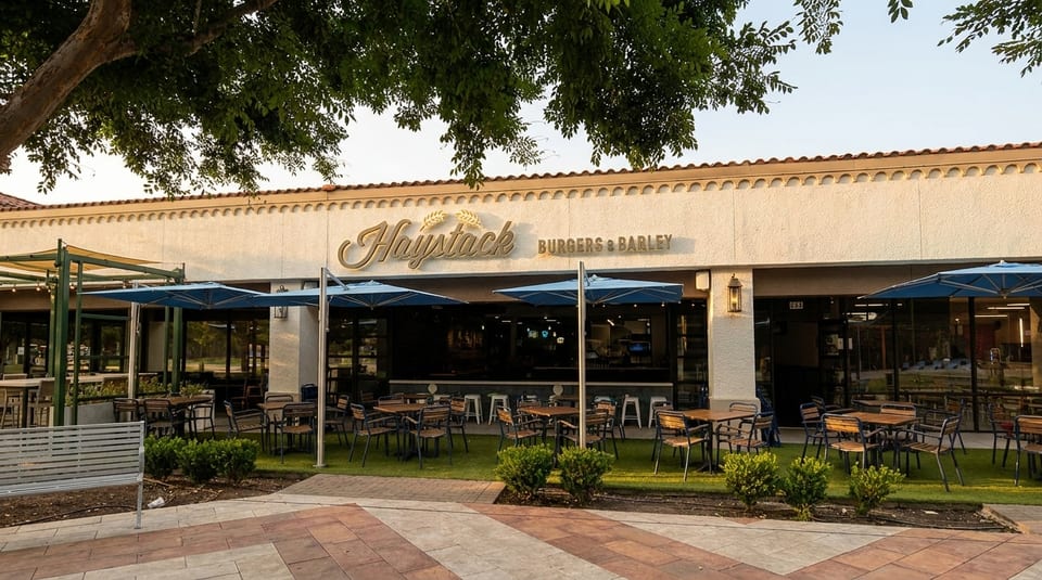 Haystack Burgers & Barley restaurant exterior with outdoor patio seating under blue umbrellas.