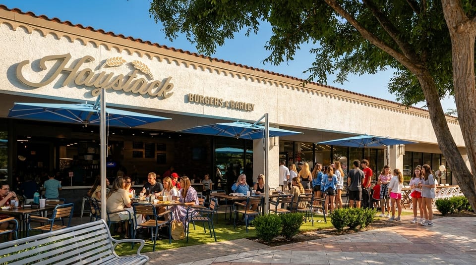 The Haystack Burgers & Barley restaurant exterior with outdoor patio seating and many customers.