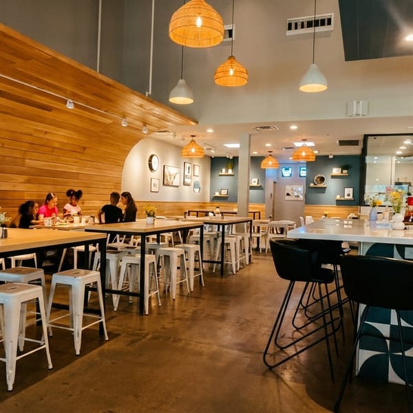 A modern restaurant interior with wooden walls, hanging lights, and a bar with patterned tiles.